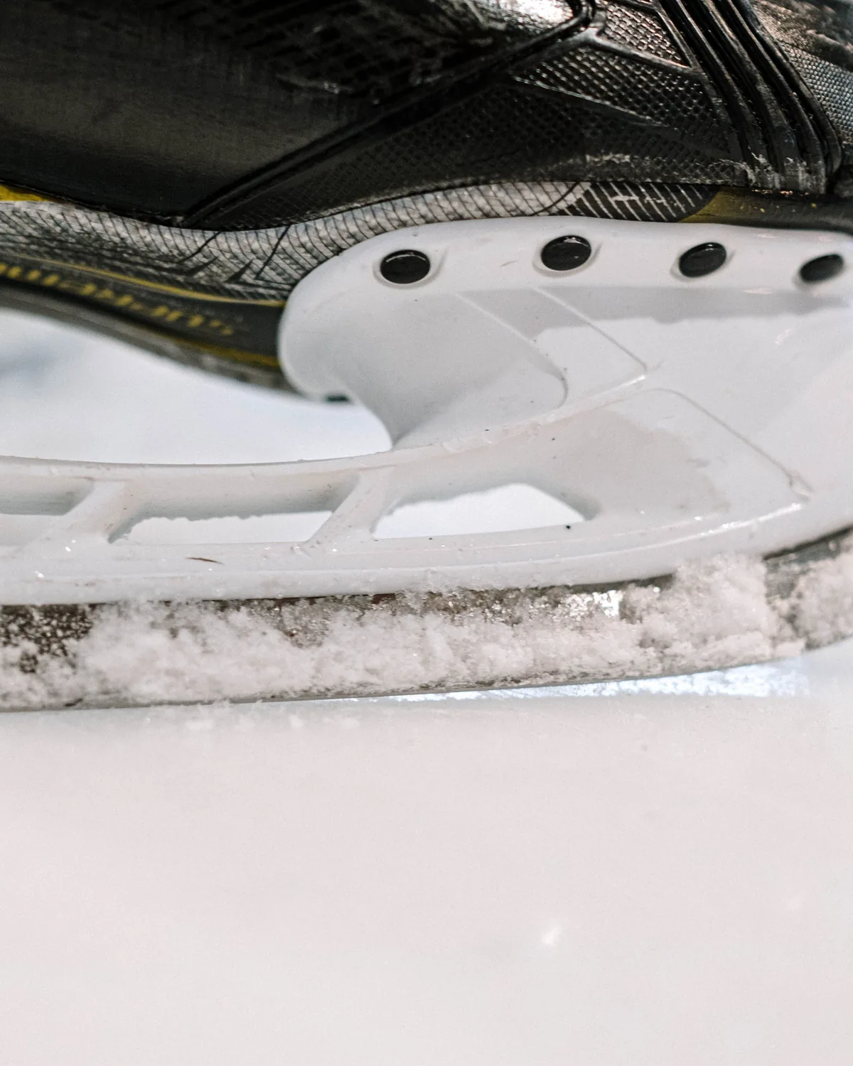 Close view of a steel hockey skate blade resting on scraped rink ice.