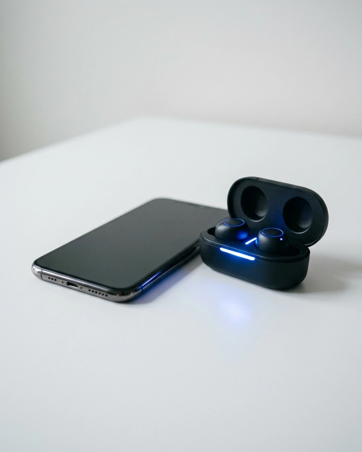 A smartphone beside an open case of wireless earbuds during pairing